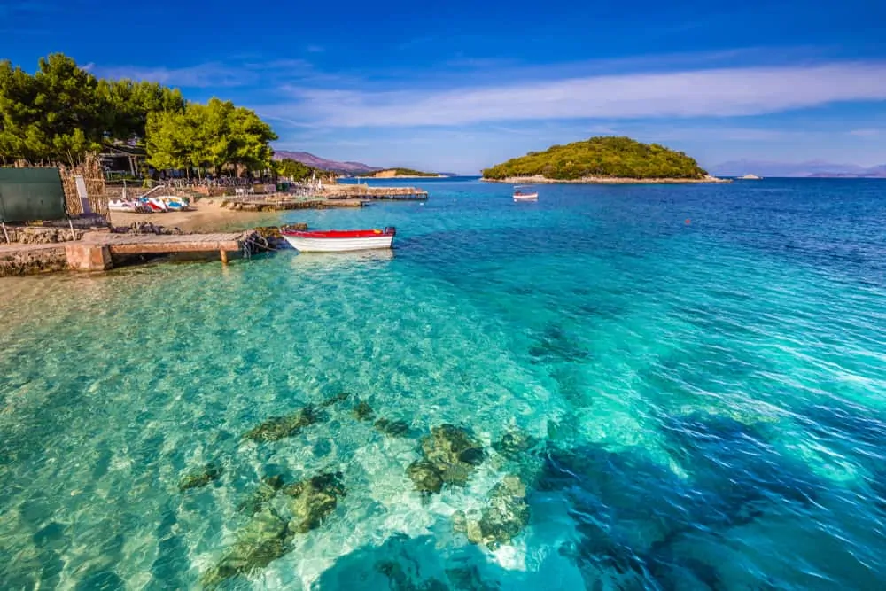 Crystal-clear turquoise water and small boats along the coastline of Ksamil, a popular beach destination in southern Albania.